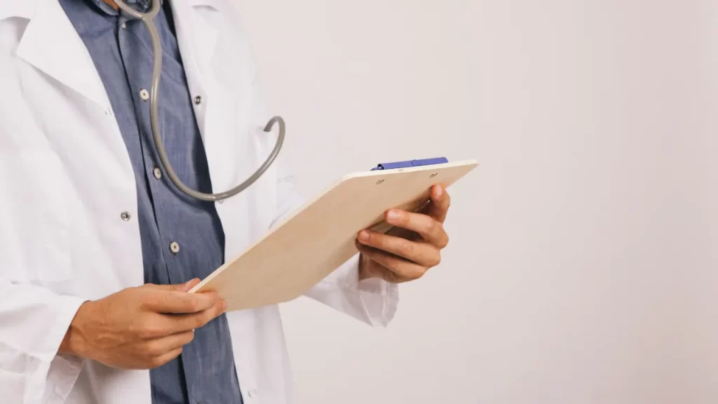 Médico segurando prancheta durante avaliação clínica para perícia médica.
